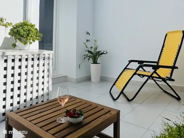 Privé terras met tweezits bankje, tafel en stoel.